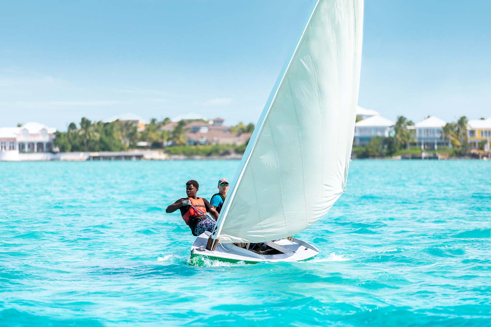 Young sailors racing a traditional Bahamian dinghy in bright Exuma water